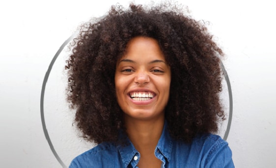 Smiling young woman with curly hair, wearing a blue shirt, happy after Canesten thrush treatment